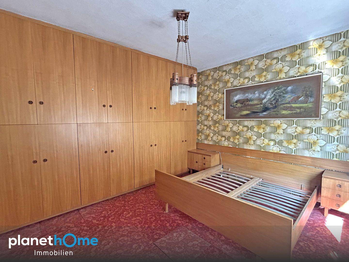 Schlafzimmer mit Einbauschränken, Doppelbett und gemusterter Tapete im Vintage-Stil.