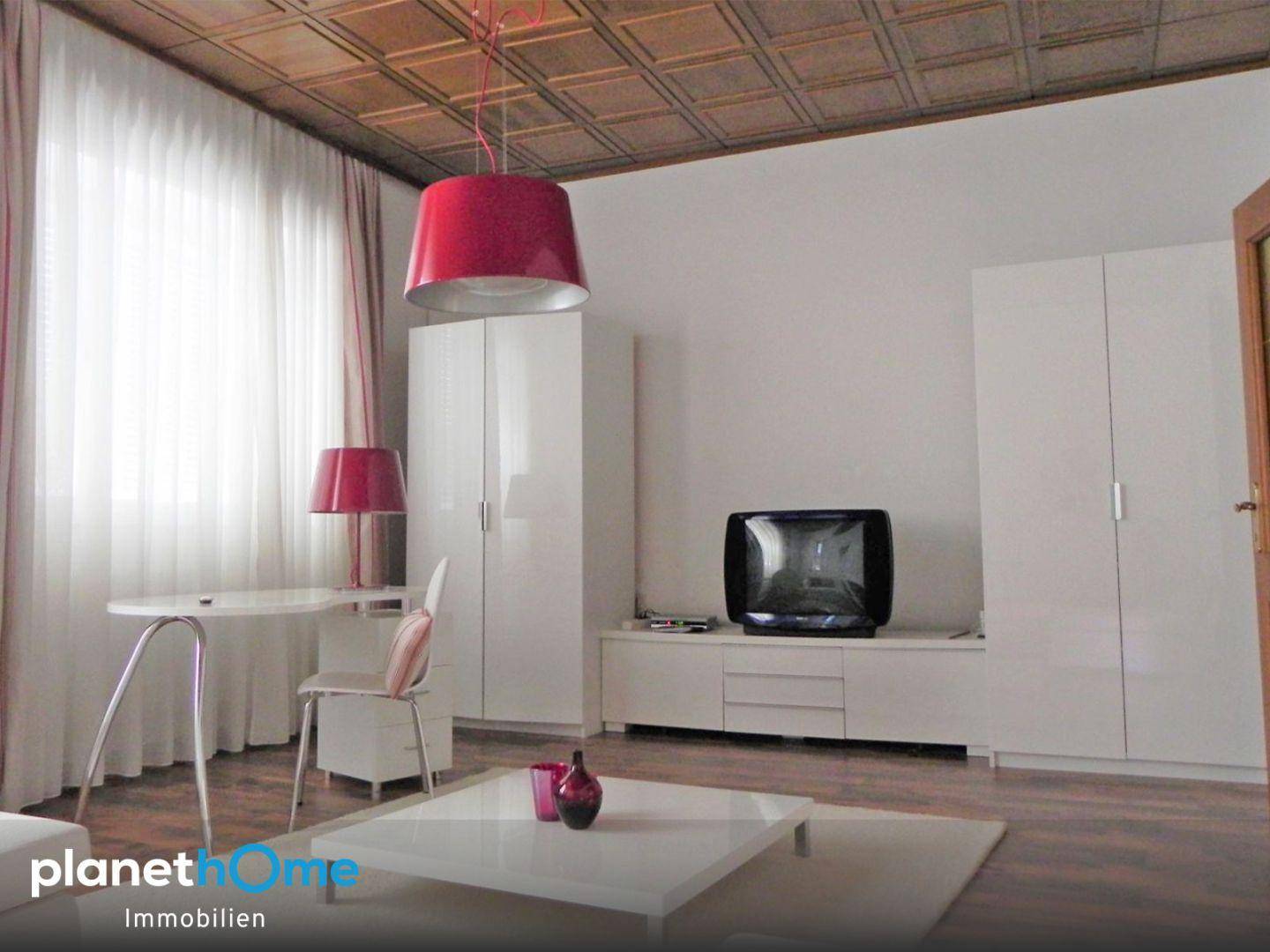 Helles Wohnzimmer mit weißer Einrichtung, roter Dekoration und einer Holzdecke.