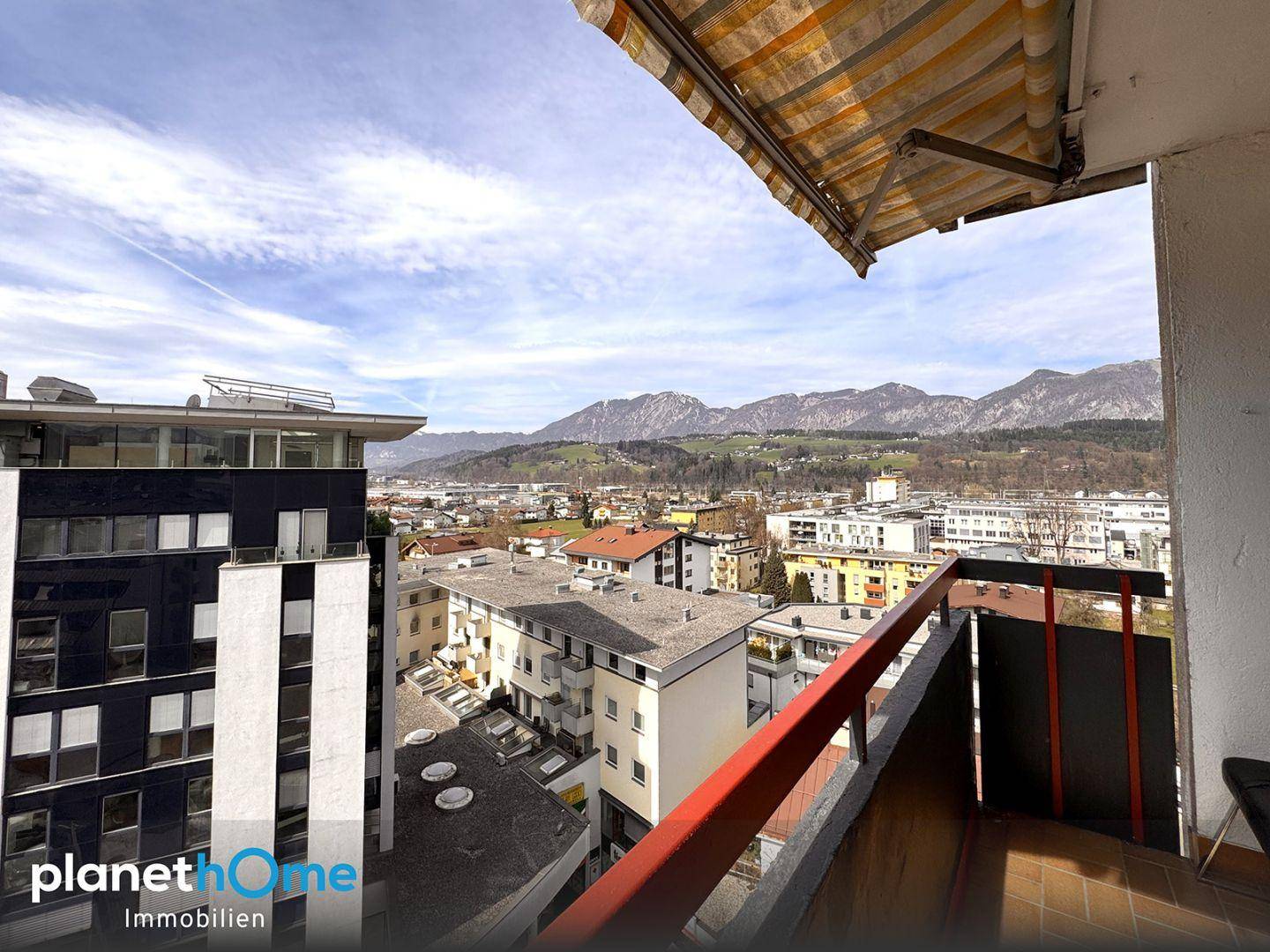 Balkon mit Markise bietet weiten Blick über die Stadt und die umliegenden Berge.