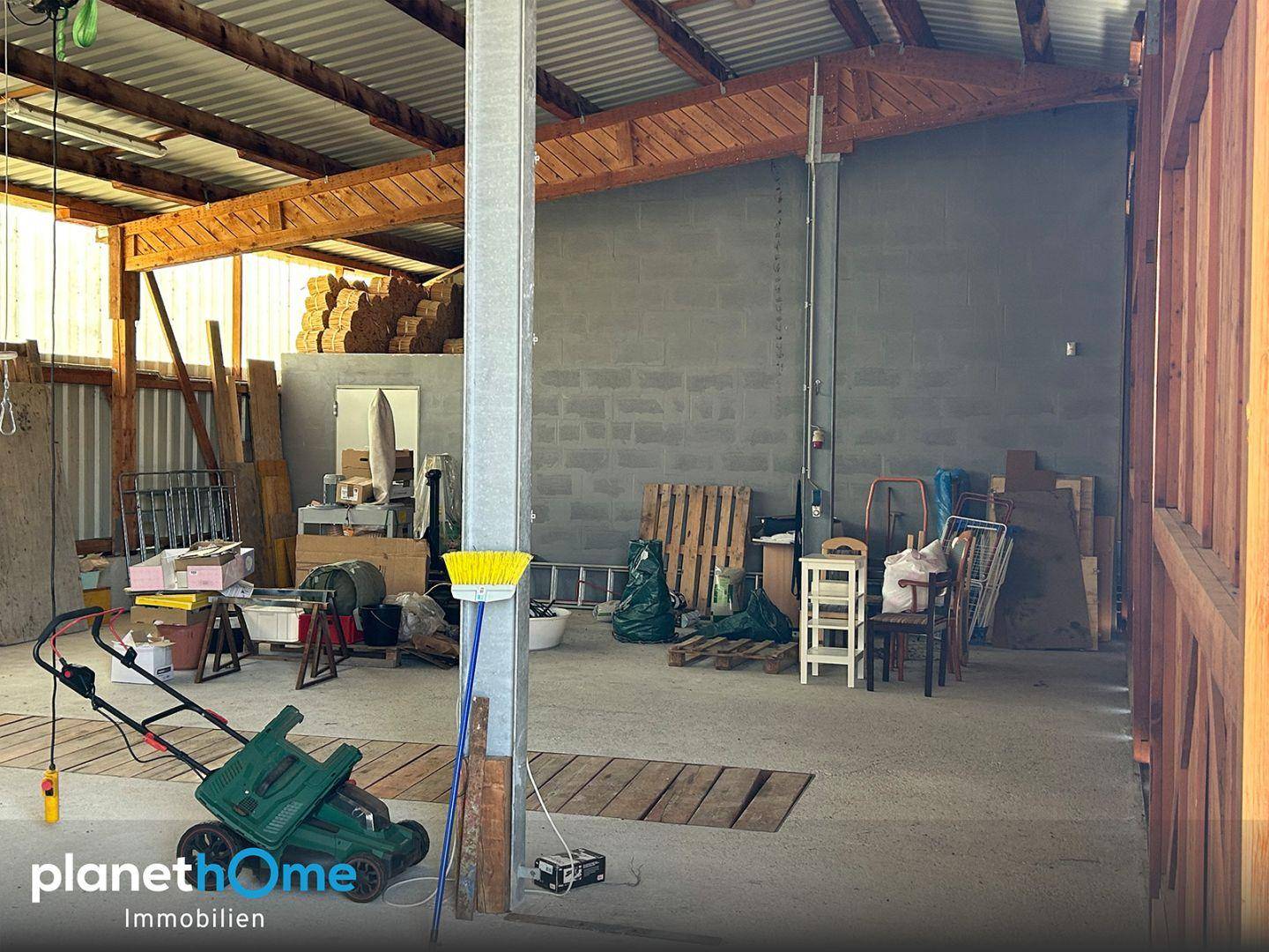 Große offene Halle mit Holzdachkonstruktion und Betonwänden, ideal als Lagerraum.