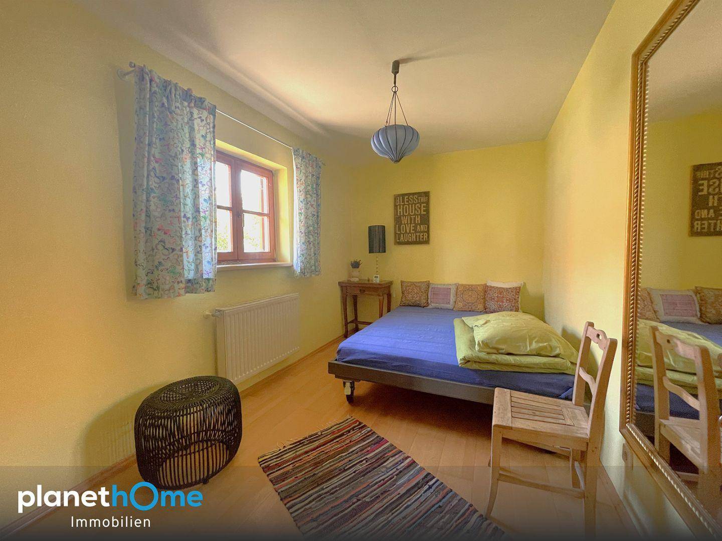 Gemütliches Schlafzimmer mit gelben Wänden, Holzboden und einem großen Spiegel.