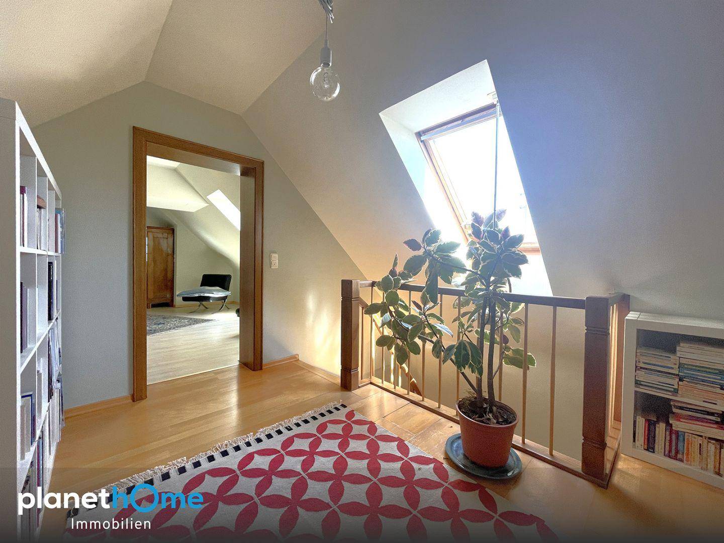 Heller Flur im Obergeschoss mit Dachfenster, Dachschrägen und integrierten Bücherregalen.