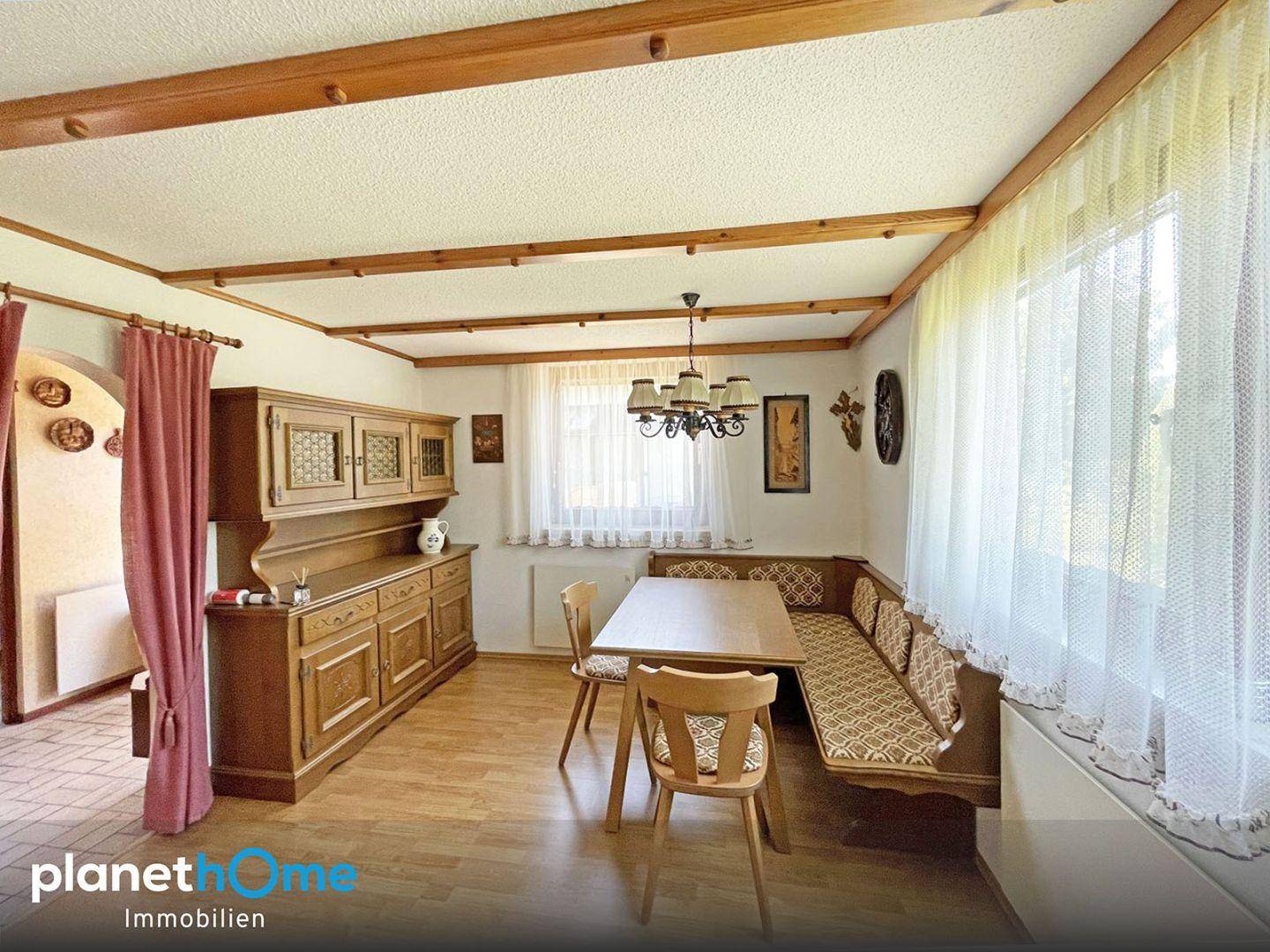 Gemütlicher Wohn-Essbereich im Landhausstil mit Holzbalkendecke und traditionellen Möbeln.