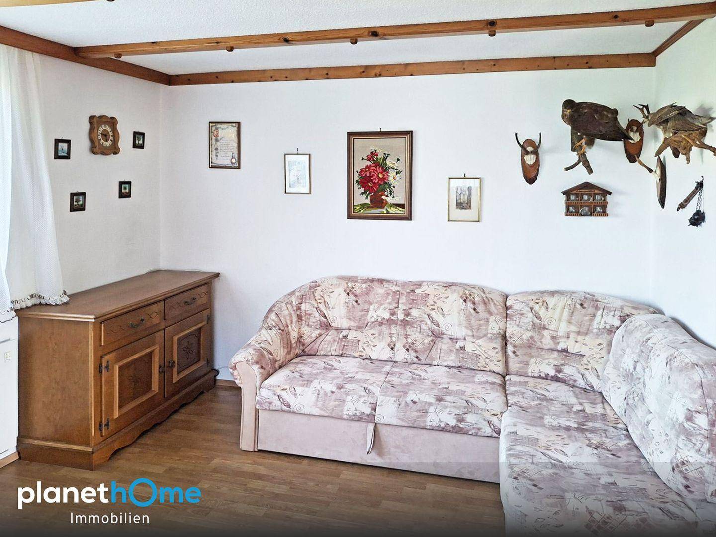 Wohnbereich mit bequemer Eckcouch, Holzmöbeln und traditioneller Dekoration an den Wänden.