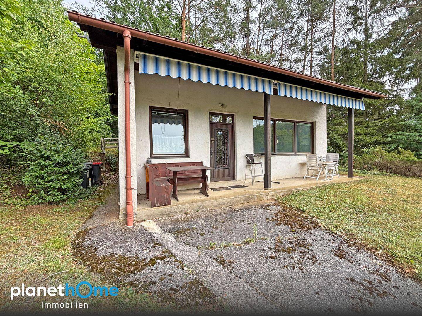 Kleines Haus mit überdachtem Eingangsbereich und Sitzgelegenheiten im Freien.