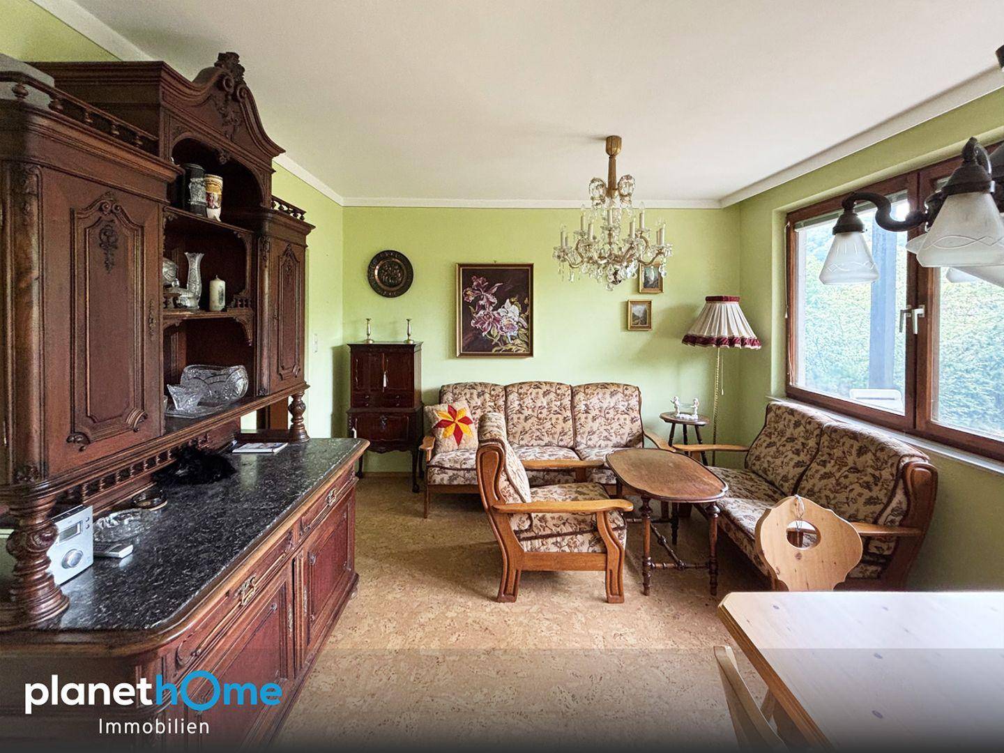 Traditionelles Wohnzimmer mit grünen Wänden, antiken Möbeln und Kronleuchter.