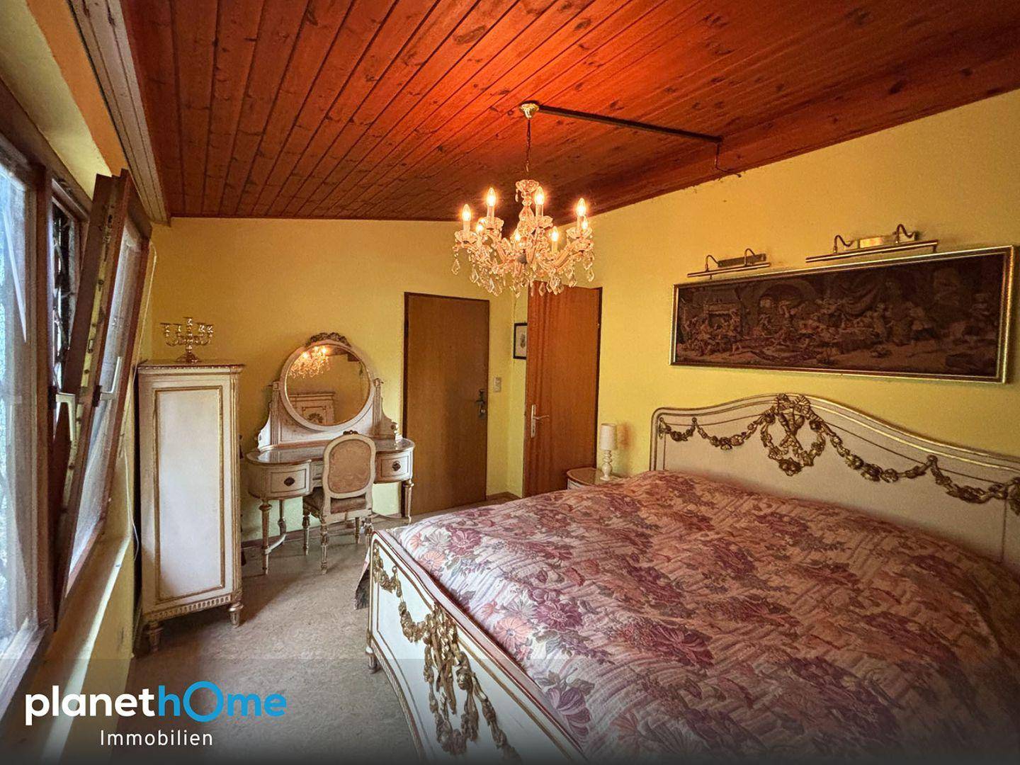 Schlafzimmer mit Holzbalkendecke, opulentem Bett und Schminktisch.