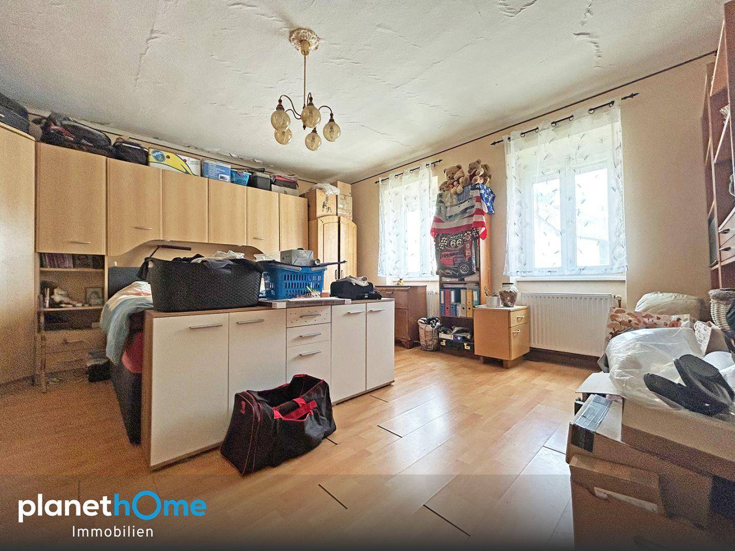 Schlafzimmer mit vielen Schränken, Laminatboden und einem Fenster mit Vorhängen.