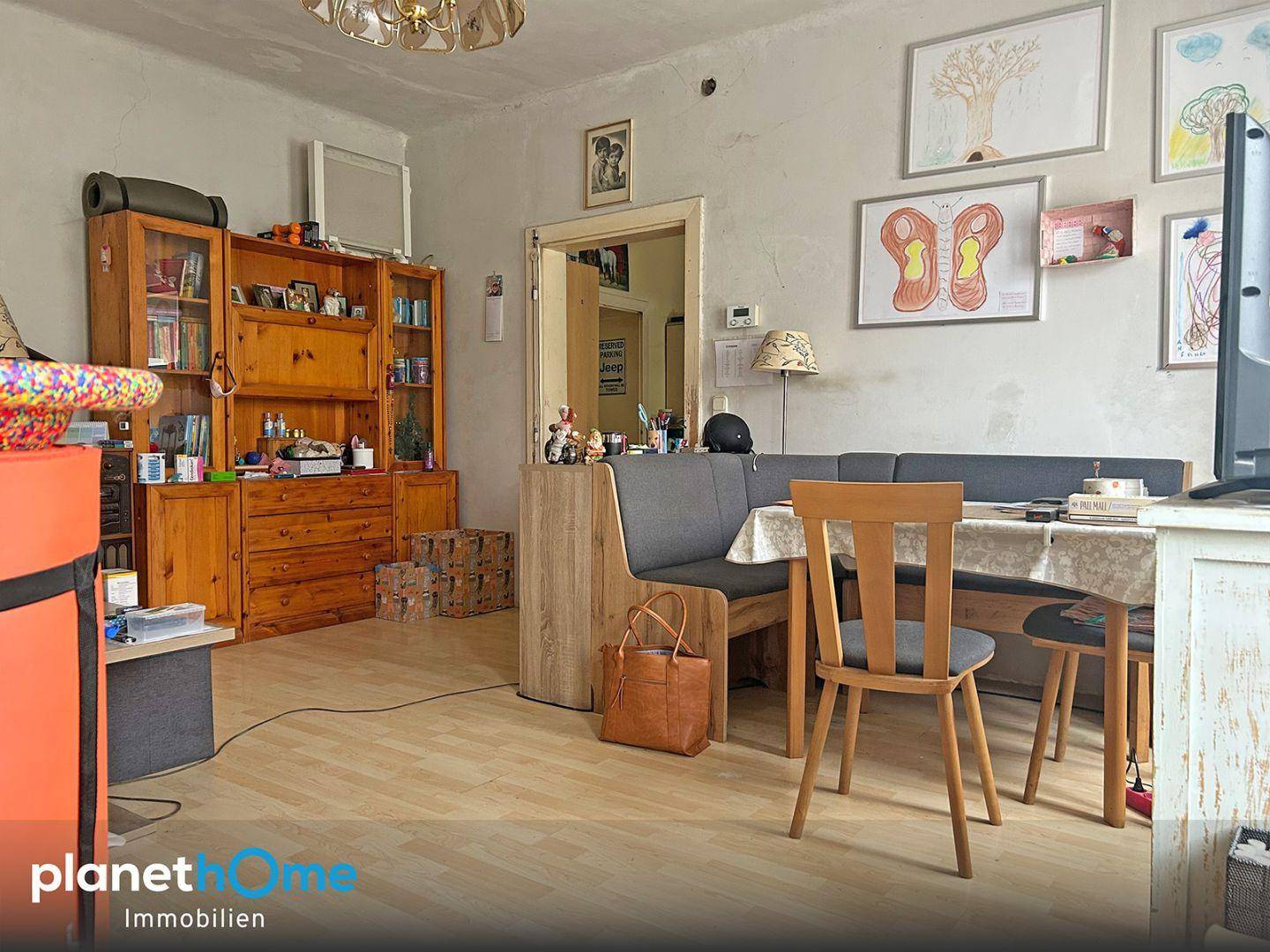 Gemütlicher Wohn- und Essbereich mit Holzmöbeln, Laminatboden und Bildern an der Wand.