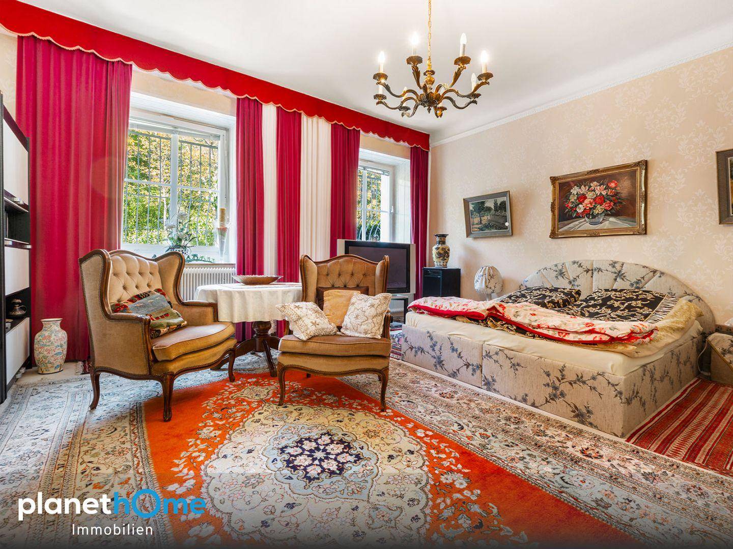 Schlafzimmer mit großem Bett, roten Vorhängen und traditioneller Einrichtung.