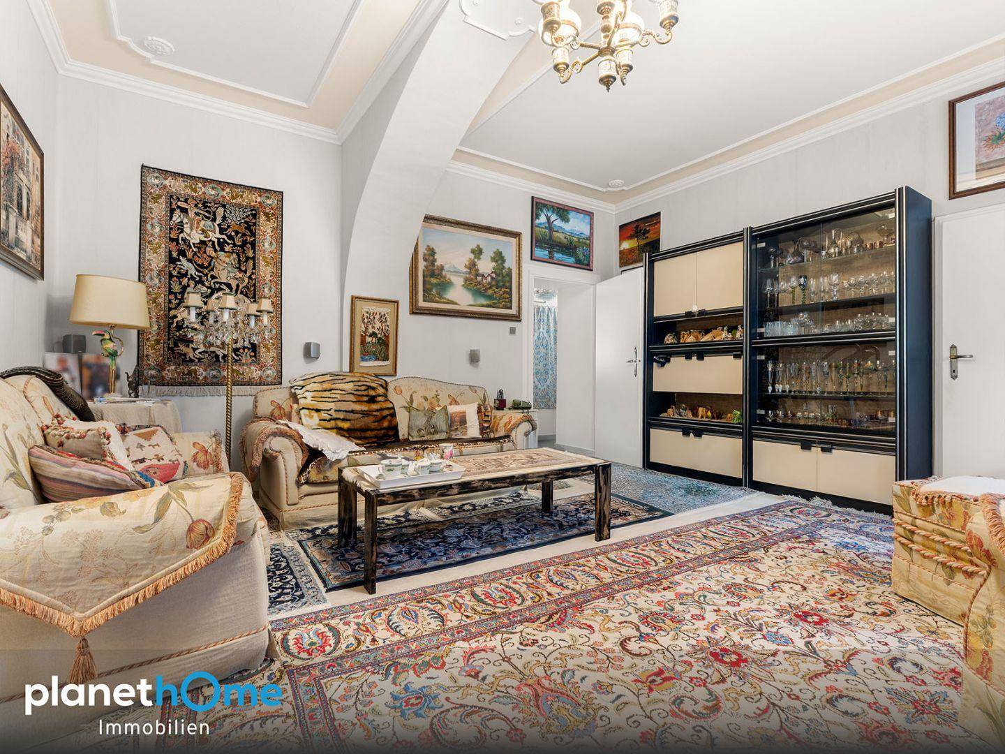 Geräumiges Wohnzimmer mit traditionellen Möbeln, Teppichen und Stuckdecke.
