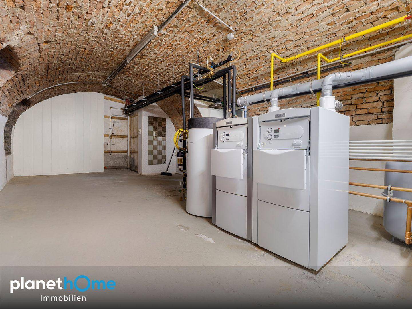 Heizraum im Keller mit moderner Heizungsanlage und Ziegelgewölbedecke.