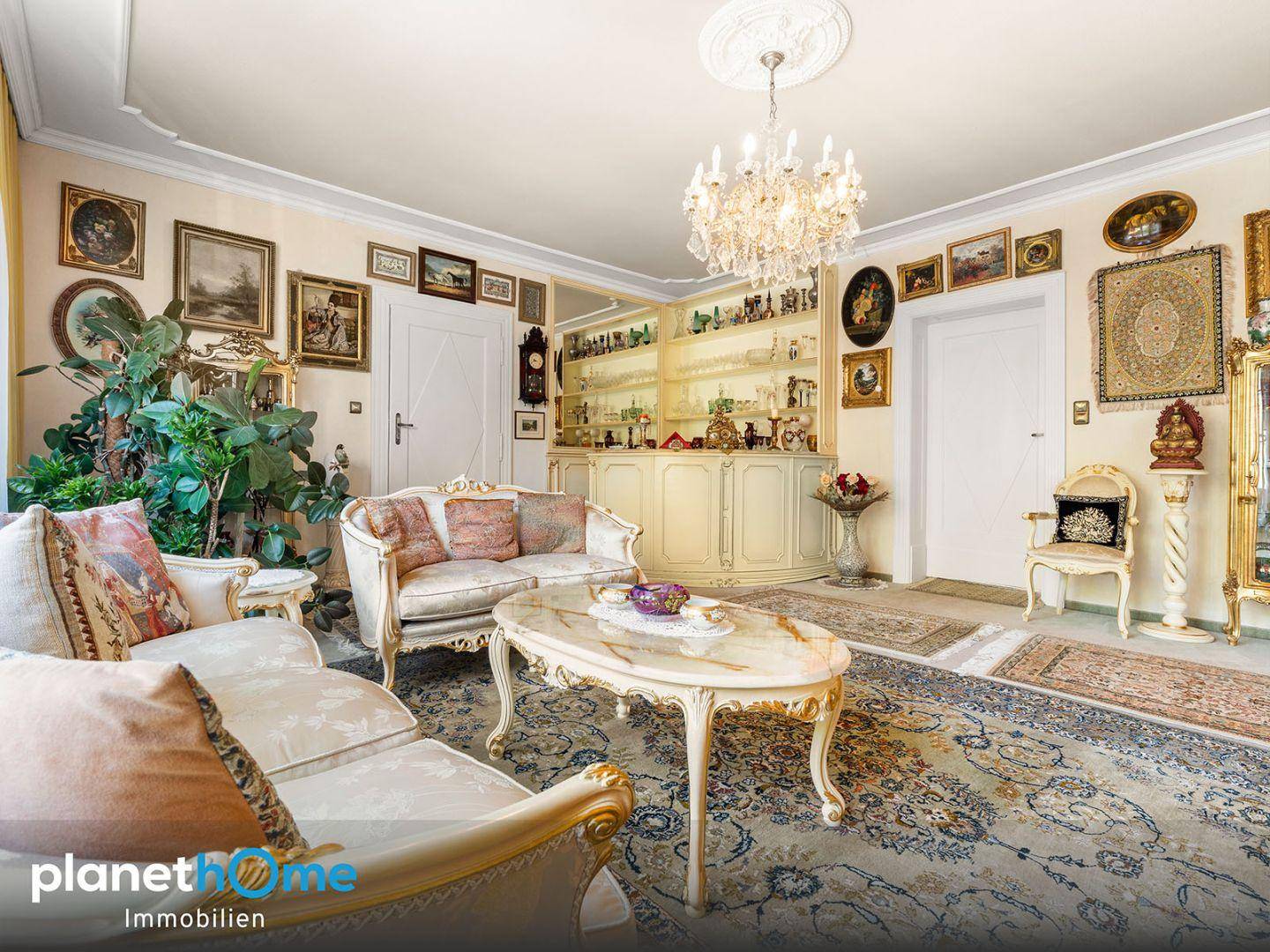 Elegantes Wohnzimmer mit Kronleuchter, Stuckdecke und klassischer Einrichtung.