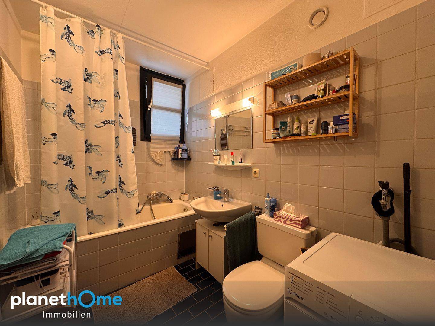 Funktionales Badezimmer mit Badewanne, Waschbecken, WC und Fliesenboden.