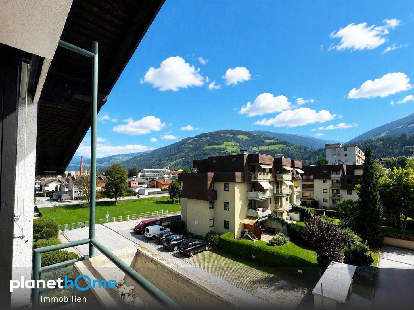 Balkon mit weitem Blick auf die umliegende Berglandschaft und Wohngebäude.