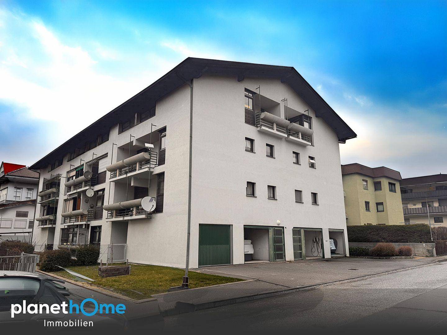 Mehrfamilienhaus mit mehreren Balkonen und Garagenzugängen im Erdgeschoss.