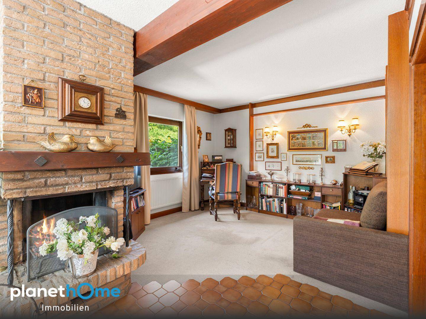 Gemütliches Wohnzimmer mit einem gemauerten Kamin, Teppichboden und traditionellen Holzmöbeln.
