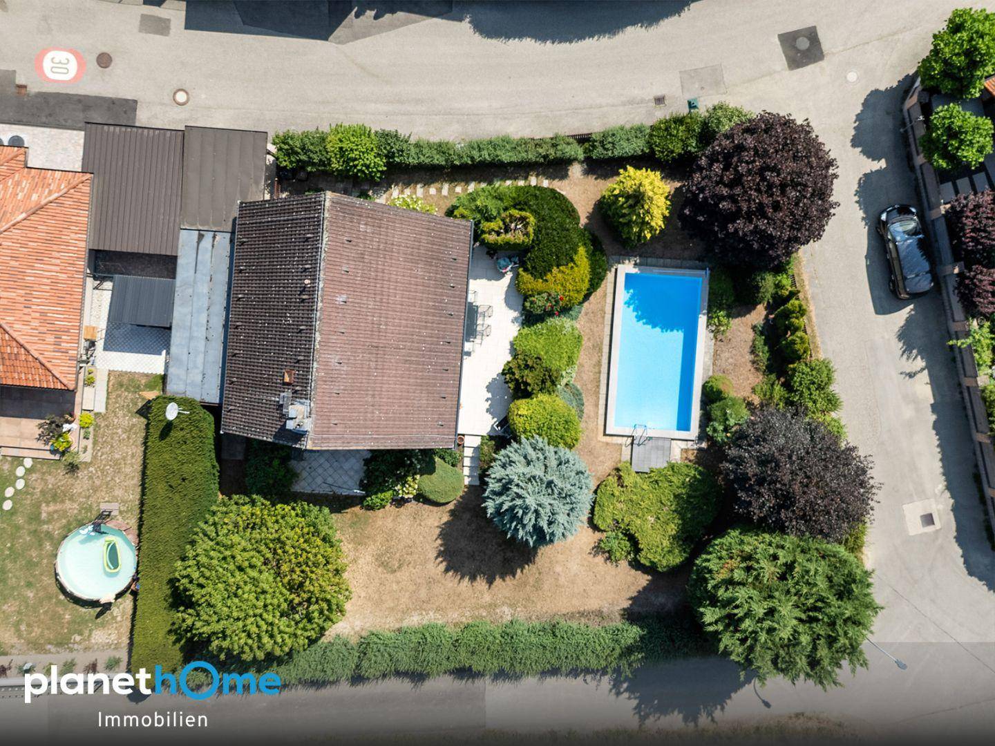 Vogelperspektive des Anwesens mit Haus, Swimmingpool und gepflegtem Gartenbereich.