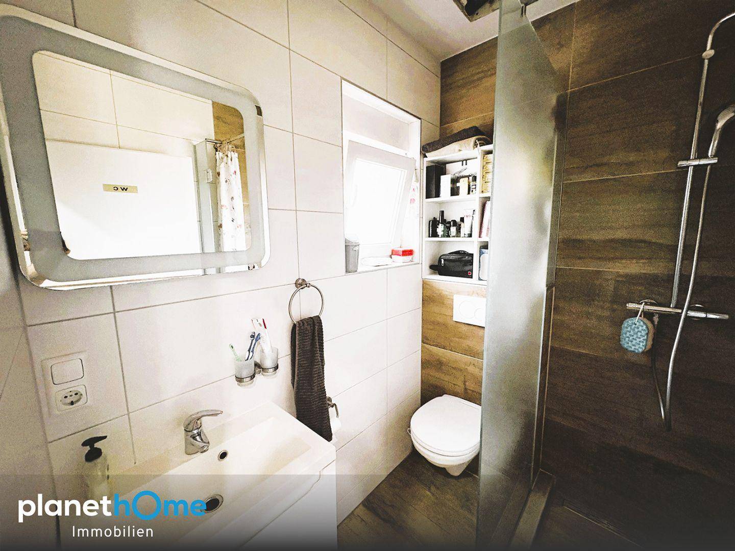 Modernes Badezimmer mit Duschkabine, WC, Waschbecken und Spiegelschrank.