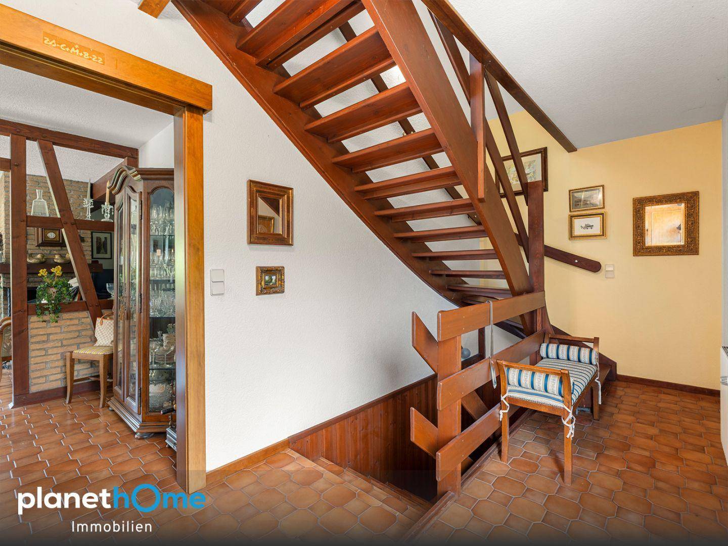 Rustikale Holztreppe in einem Flur mit Terrakotta-Fliesenboden und traditioneller Einrichtung.