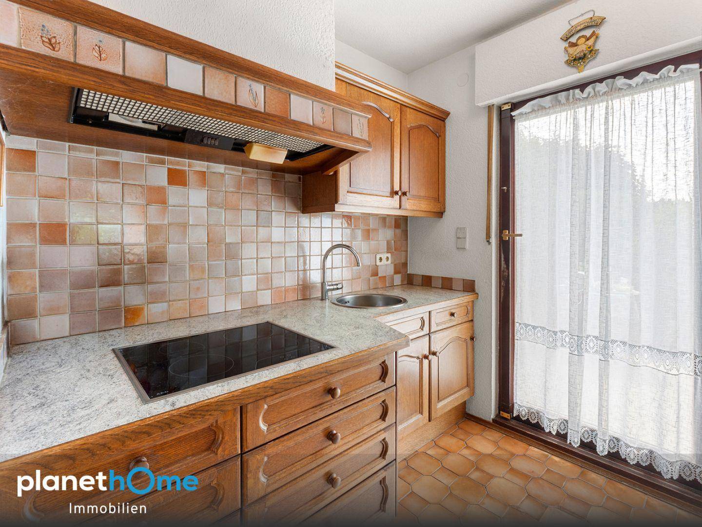 Traditionelle Holzküche mit Granit-Arbeitsplatte, Induktionskochfeld und Zugang zum Außenbereich.