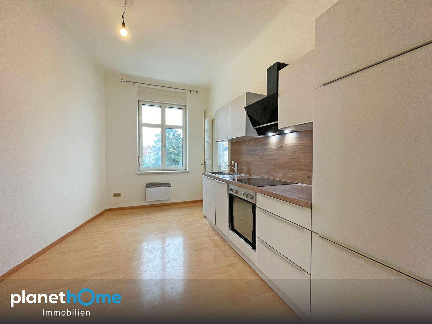 Moderne Einbauküche mit weißen Schränken, Holzoptik-Arbeitsplatte und integrierten Geräten.