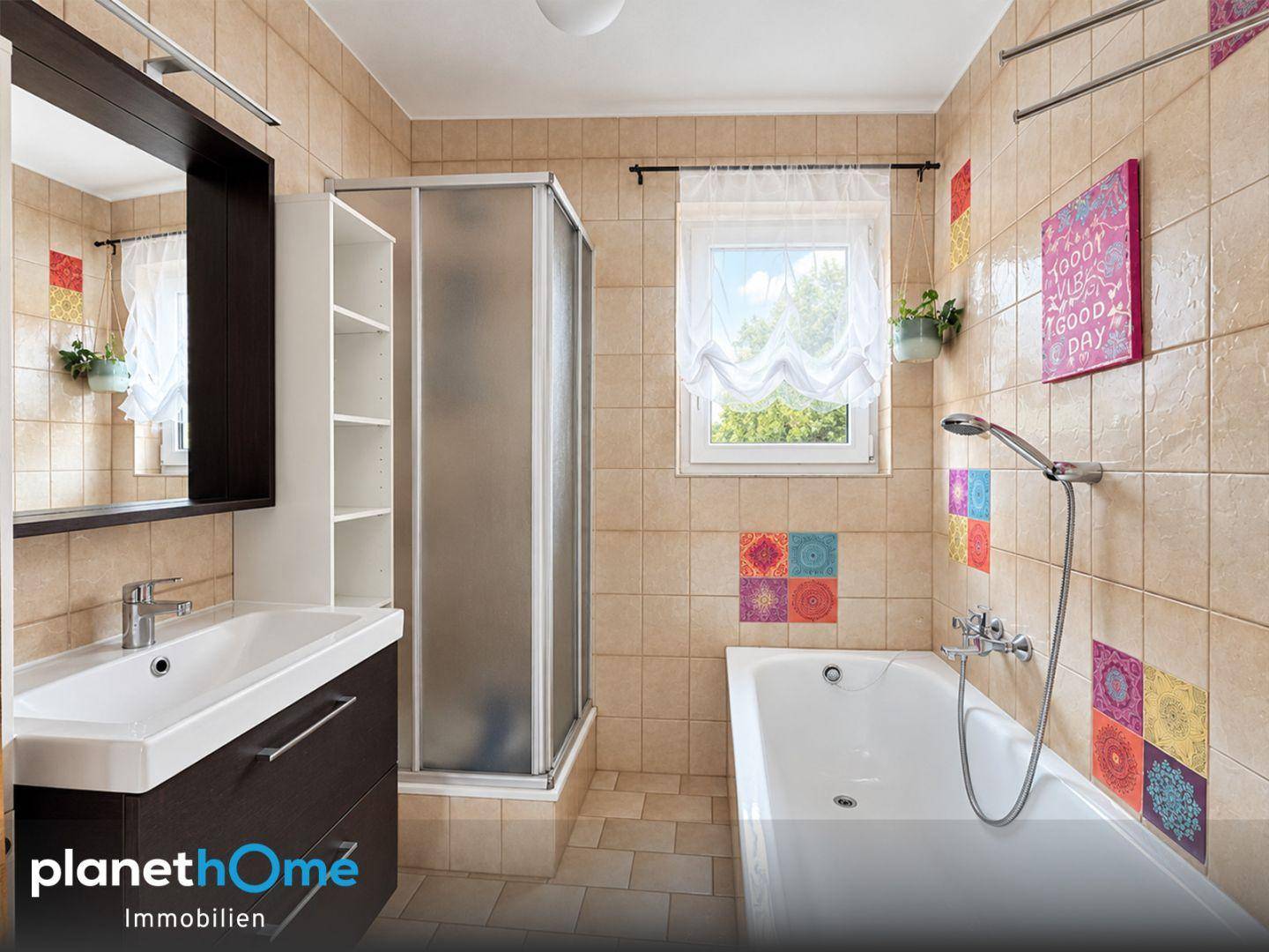 Badezimmer mit beigefarbenen Fliesen, Badewanne, Dusche und Fenster.