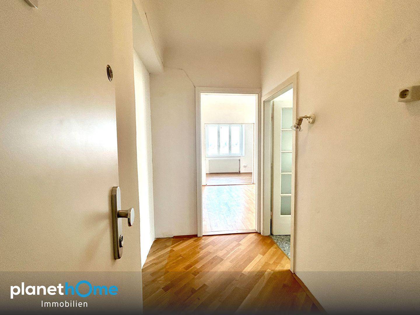 Heller Flur mit Parkettboden, der zu verschiedenen Räumen der Wohnung führt.