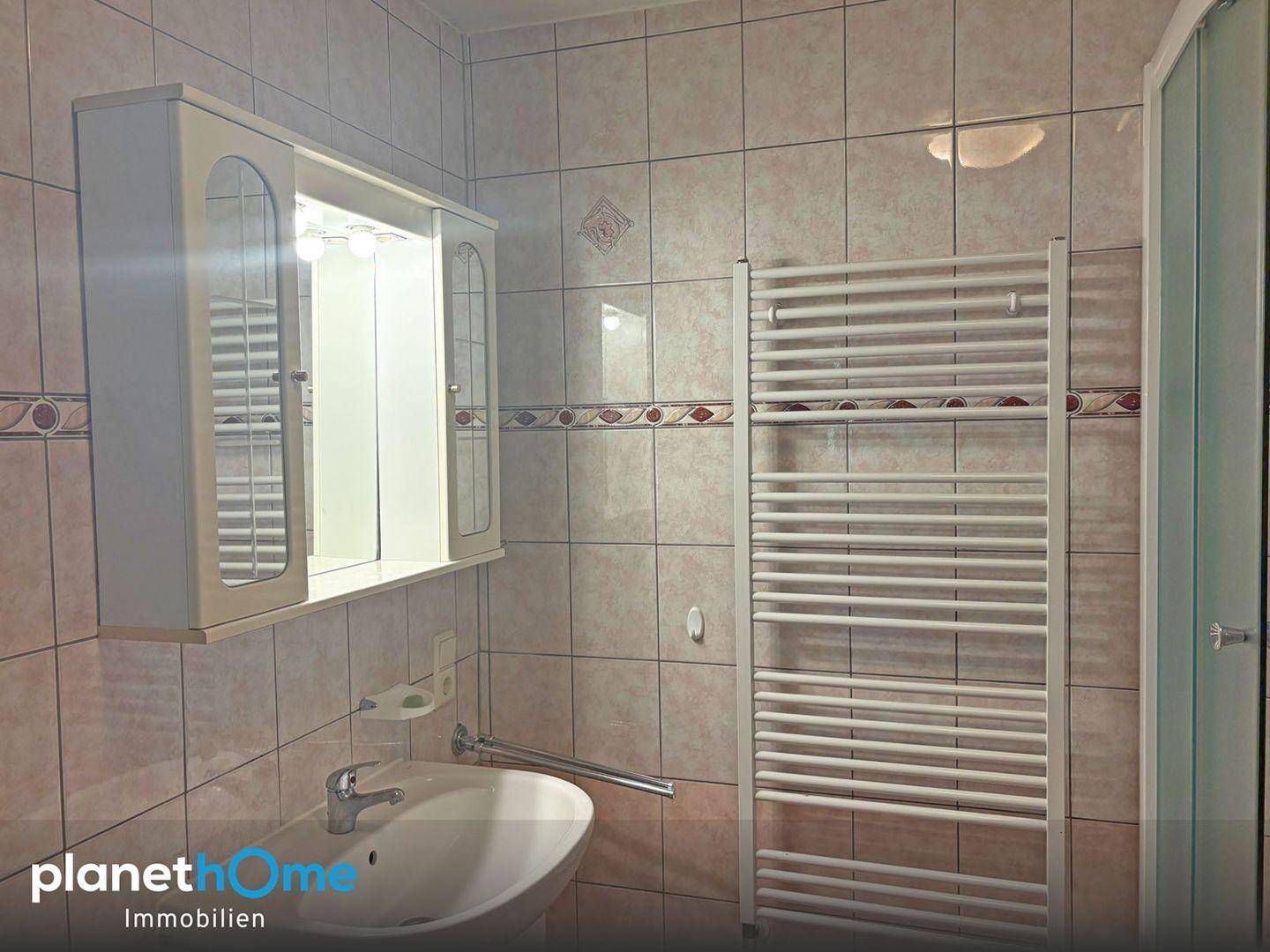 Badezimmer mit Waschbecken, Spiegelschrank und beheiztem Handtuchhalter.