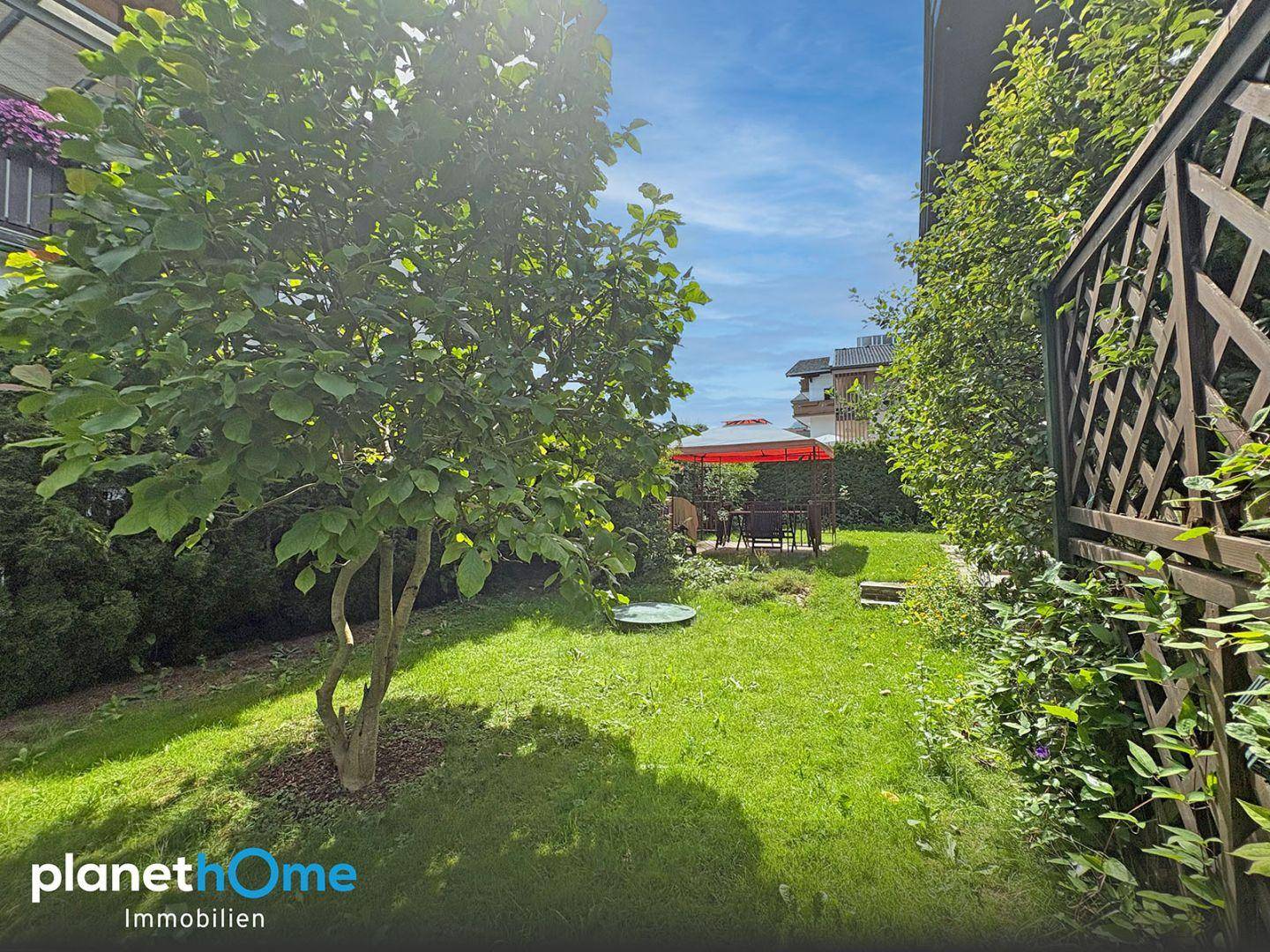 Gepflegter Garten mit Baum und einem Pavillon im Hintergrund für entspannte Stunden.