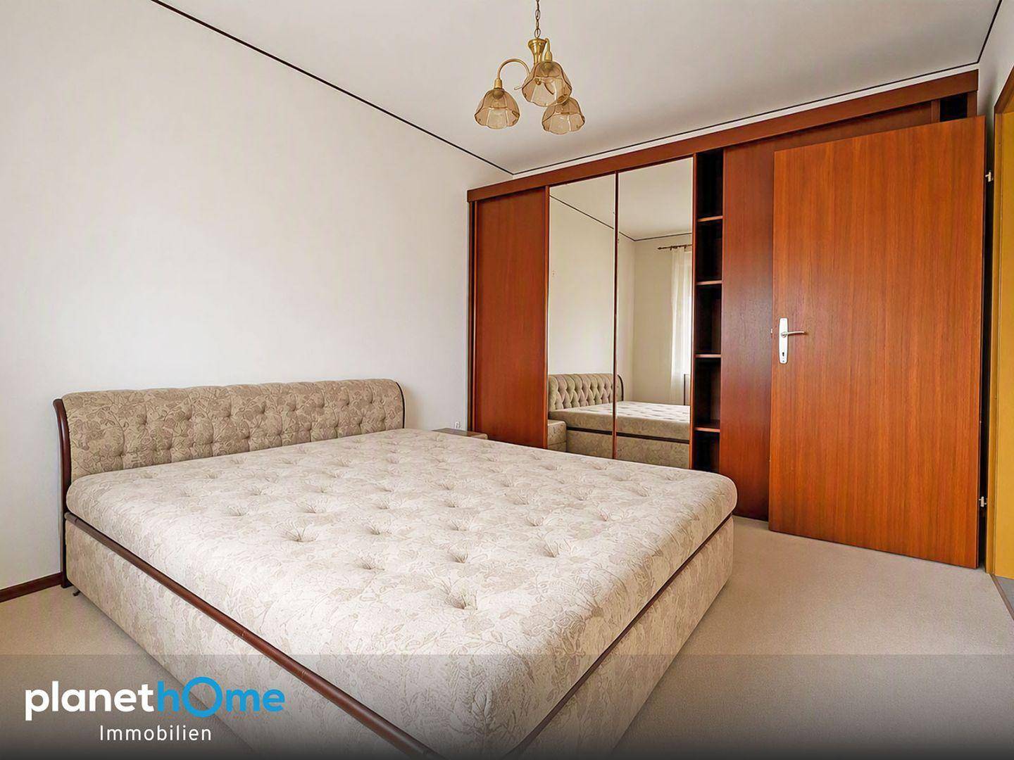 Schlafzimmer mit großem Doppelbett und einem geräumigen Kleiderschrank mit Spiegeltüren.
