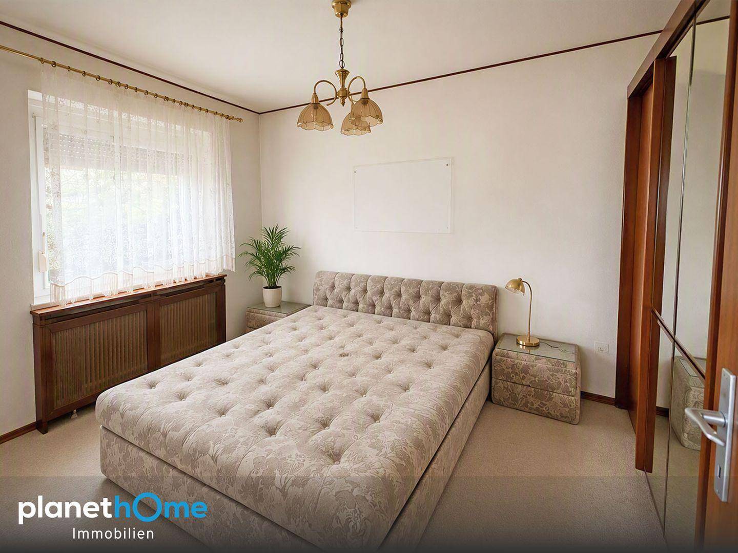 Helles Schlafzimmer mit Fenster, Vorhängen und einem Nachttisch neben dem bequemen Bett.