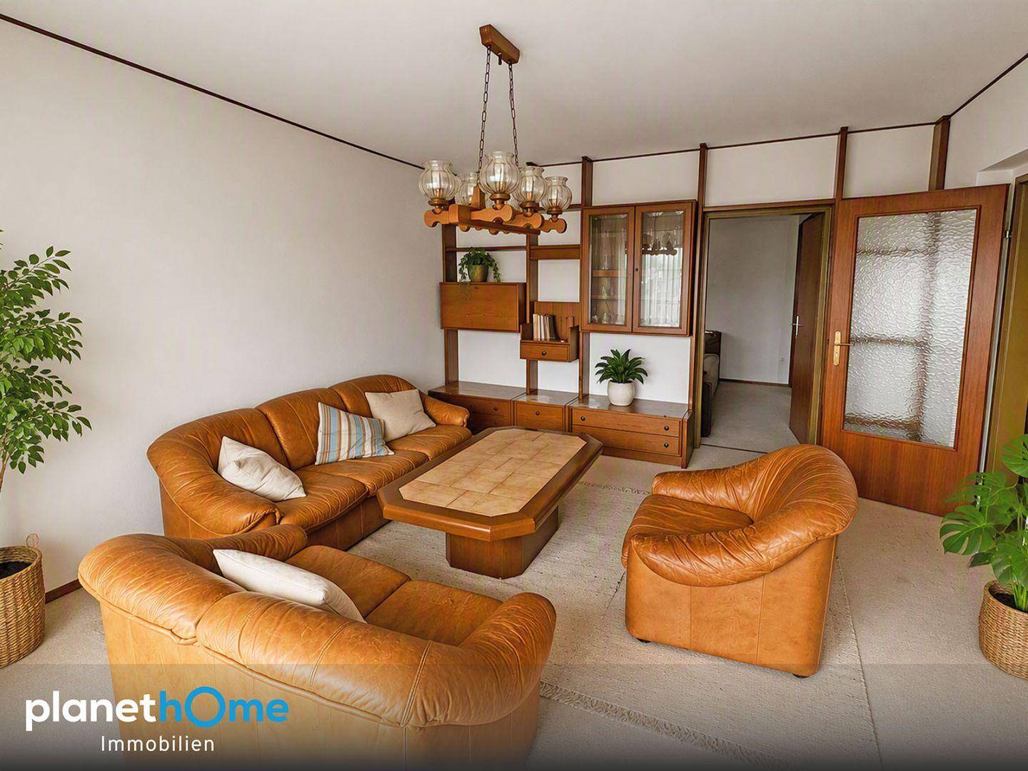 Gemütliches Wohnzimmer mit braunen Ledersofas, Holztisch und einer passenden Schrankwand.