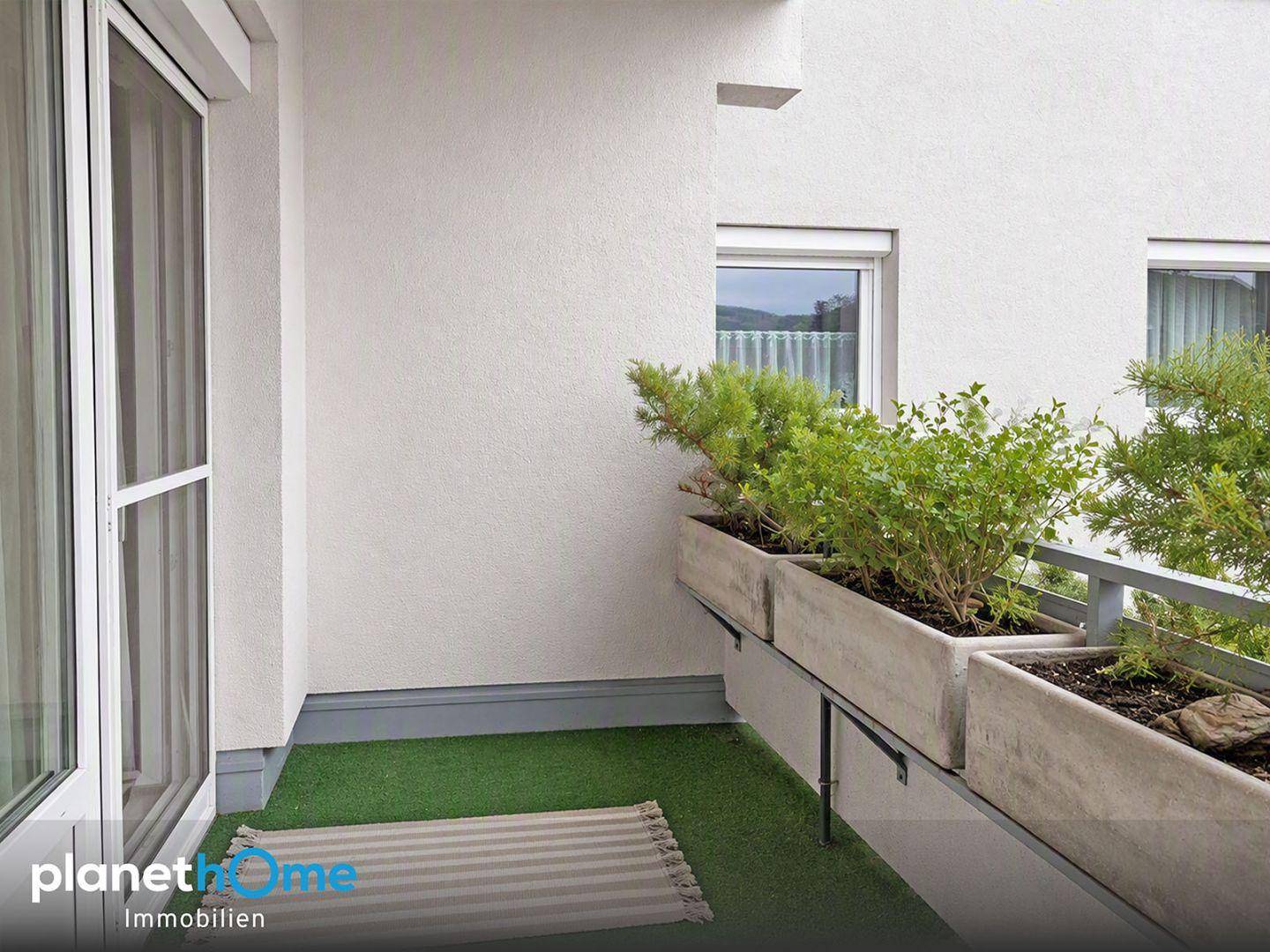 Kleiner Balkon mit Kunstrasen und Pflanzkästen, ideal für Entspannung im Freien.