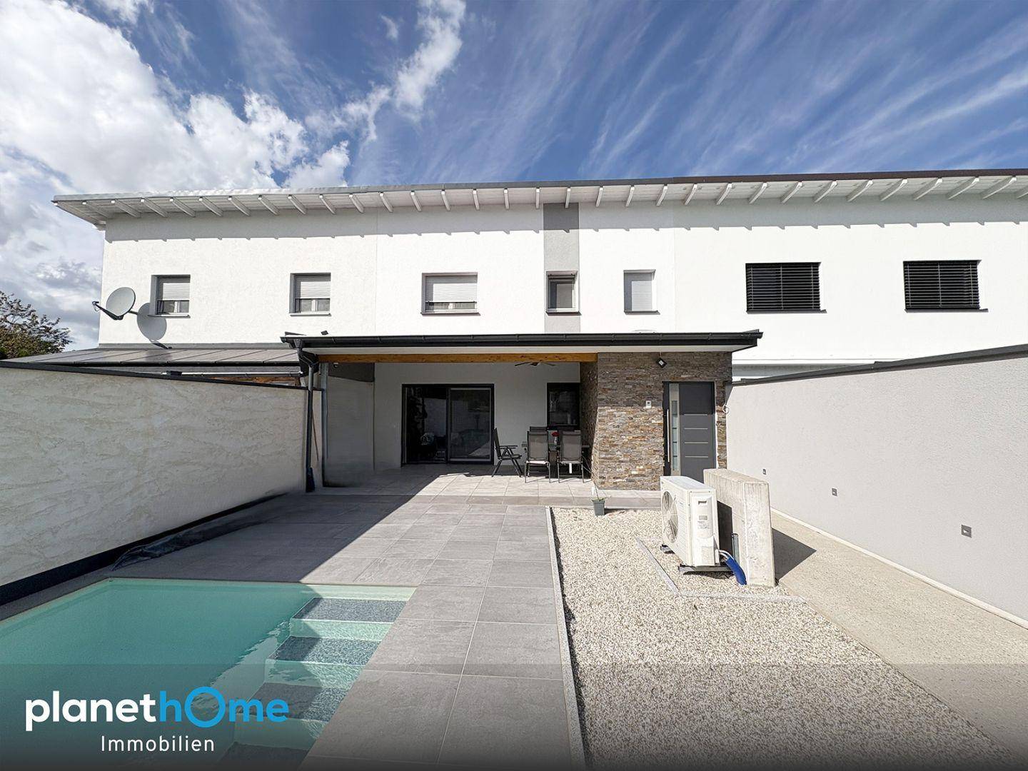 Moderner Hinterhof mit privatem Pool, gepflasterter Terrasse und Sitzbereich unter blauem Himmel.