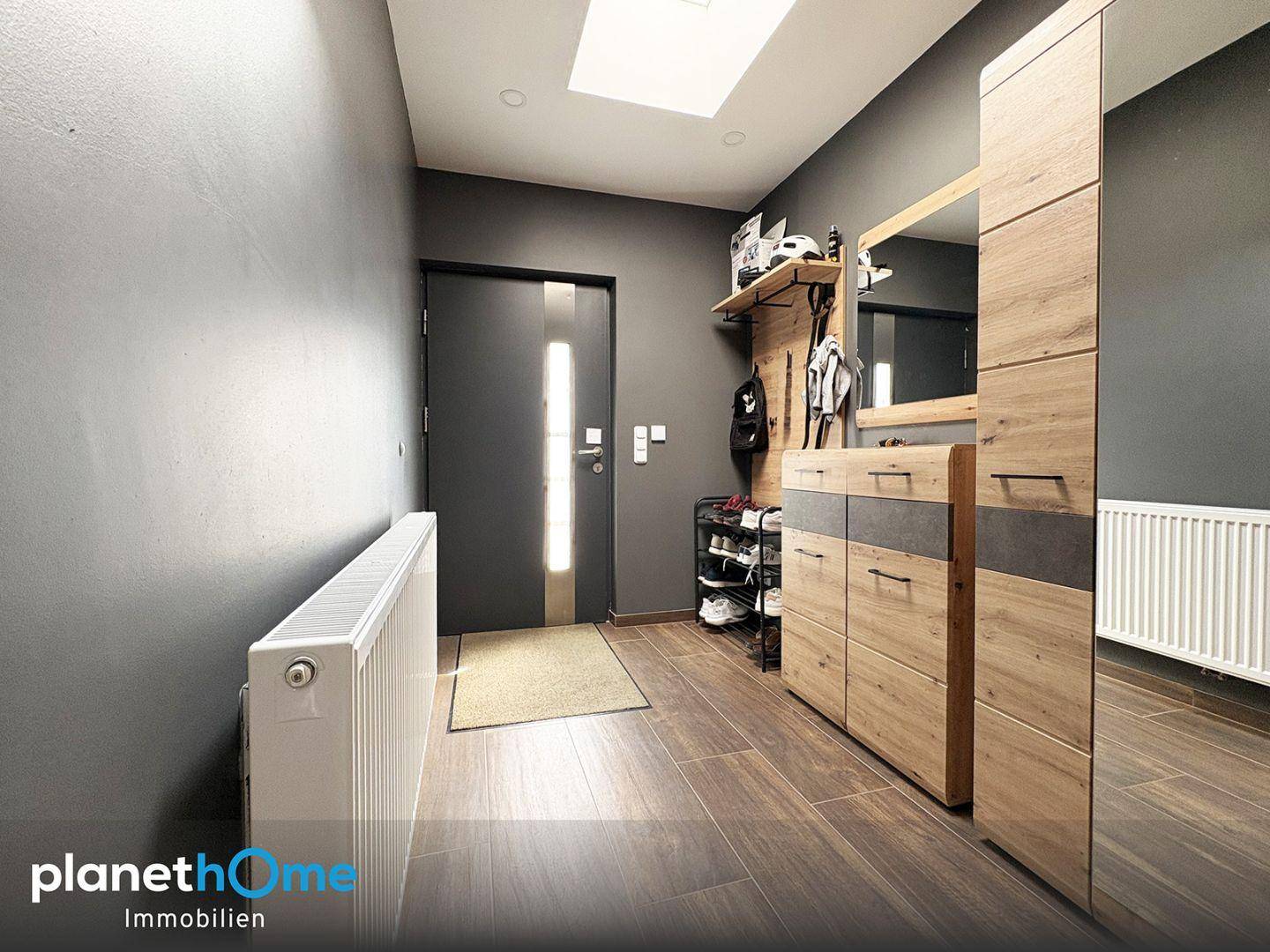Moderner Eingangsbereich mit Holzoptikboden, Garderobe und einem Oberlicht für natürliches Licht.