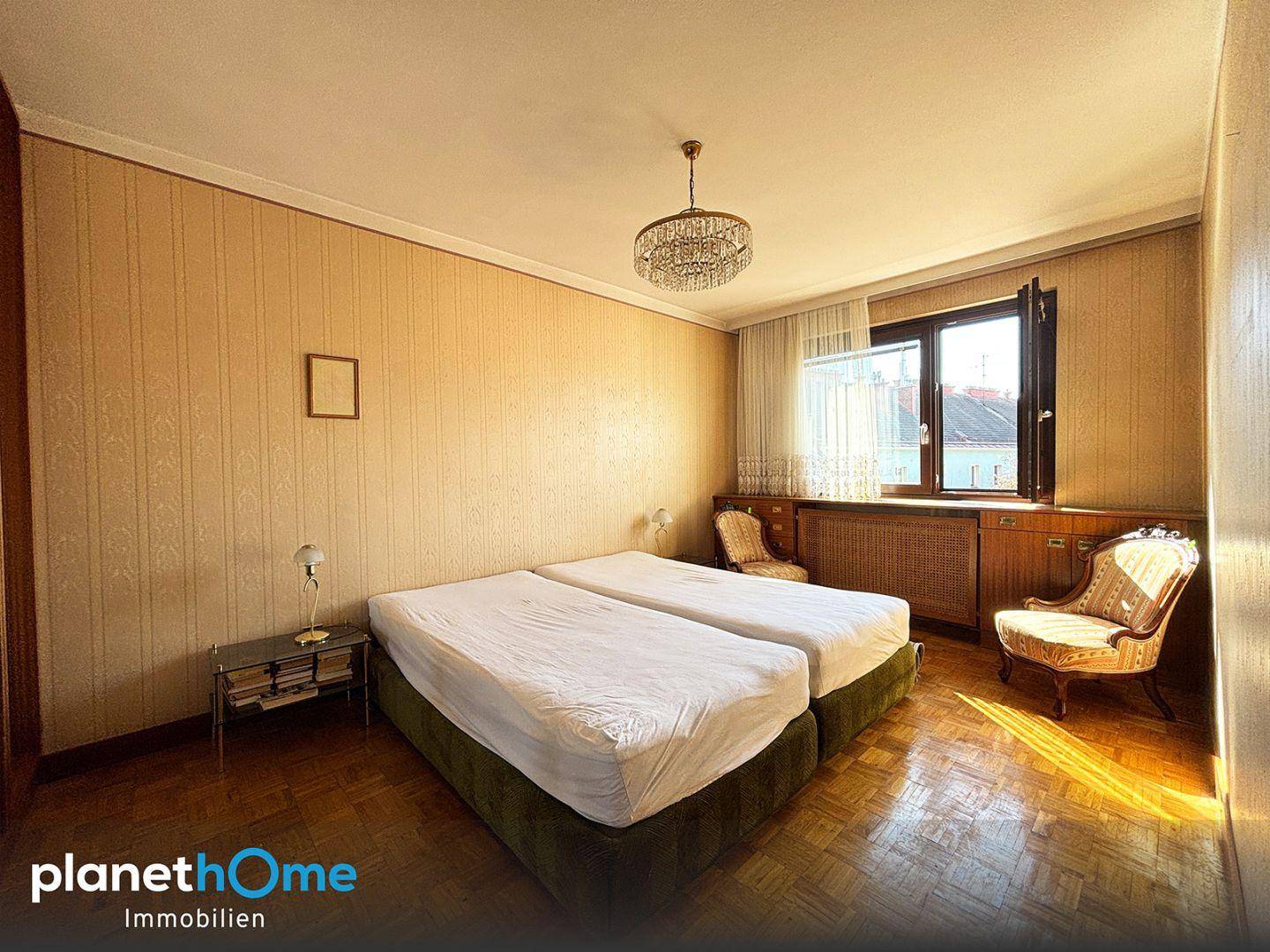 Schlafzimmer im Vintage-Stil mit zwei Einzelbetten, gemusterter Tapete und Parkettboden.