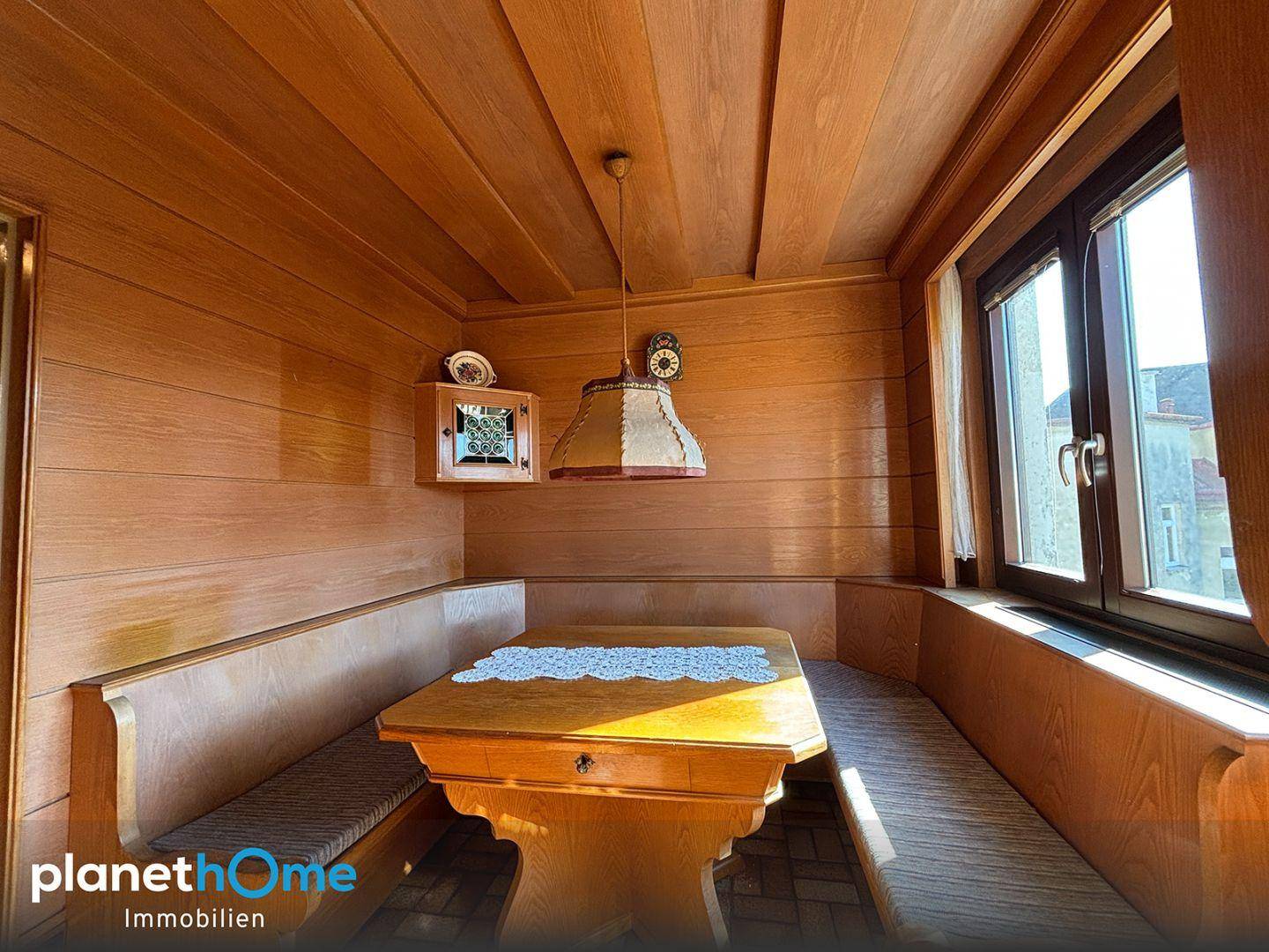 Traditioneller Essbereich mit Holzvertäfelung, Holztisch und Blick nach draußen.
