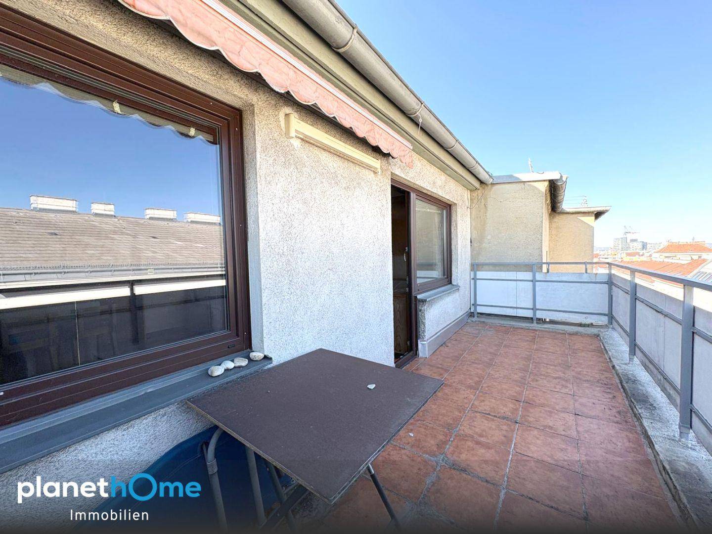 Einfacher Balkon mit kleinem Tisch und Blick auf die umliegenden Gebäude.
