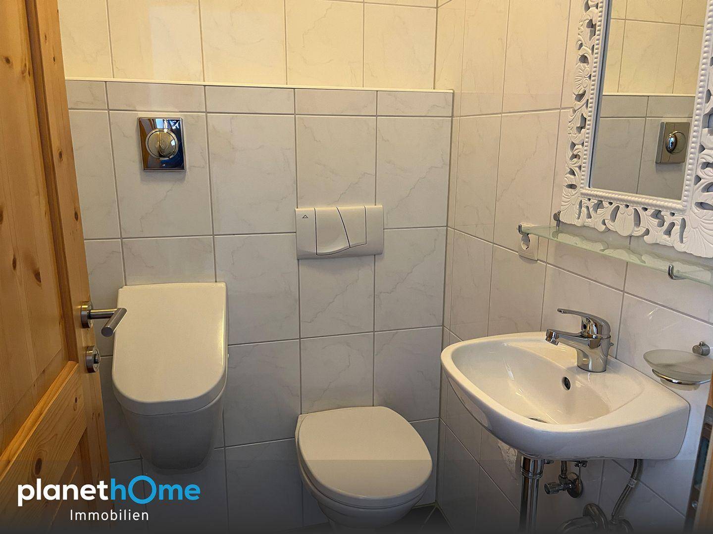 Kleines Gäste-WC mit Wand-WC, Waschbecken und weißen Fliesen.