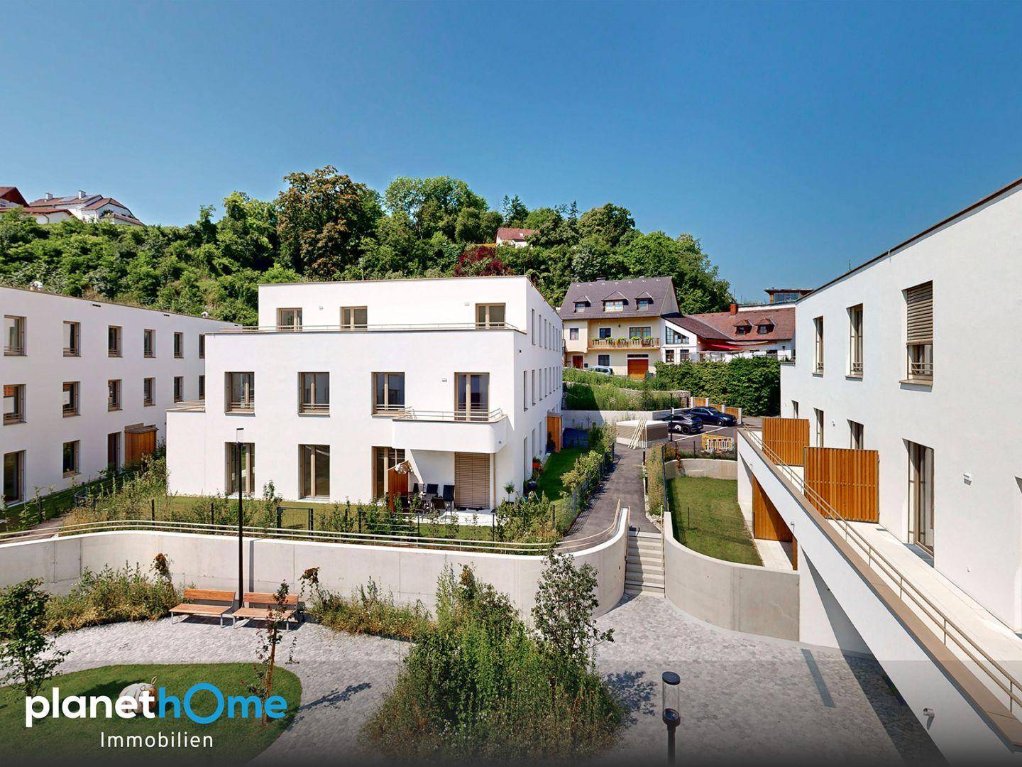 Gepflegter Innenhof mit Grünflächen und modernen Wohngebäuden in sonniger Lage.