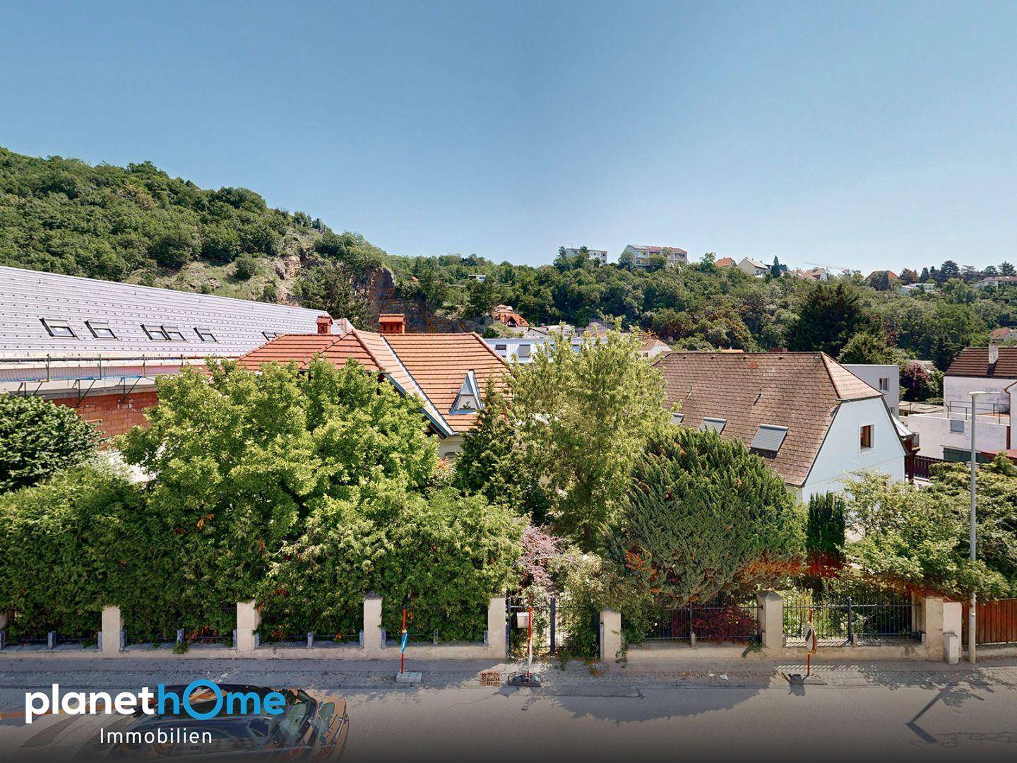 Weitläufiger Blick über Dächer und grüne Hügel in einer ruhigen Wohngegend.