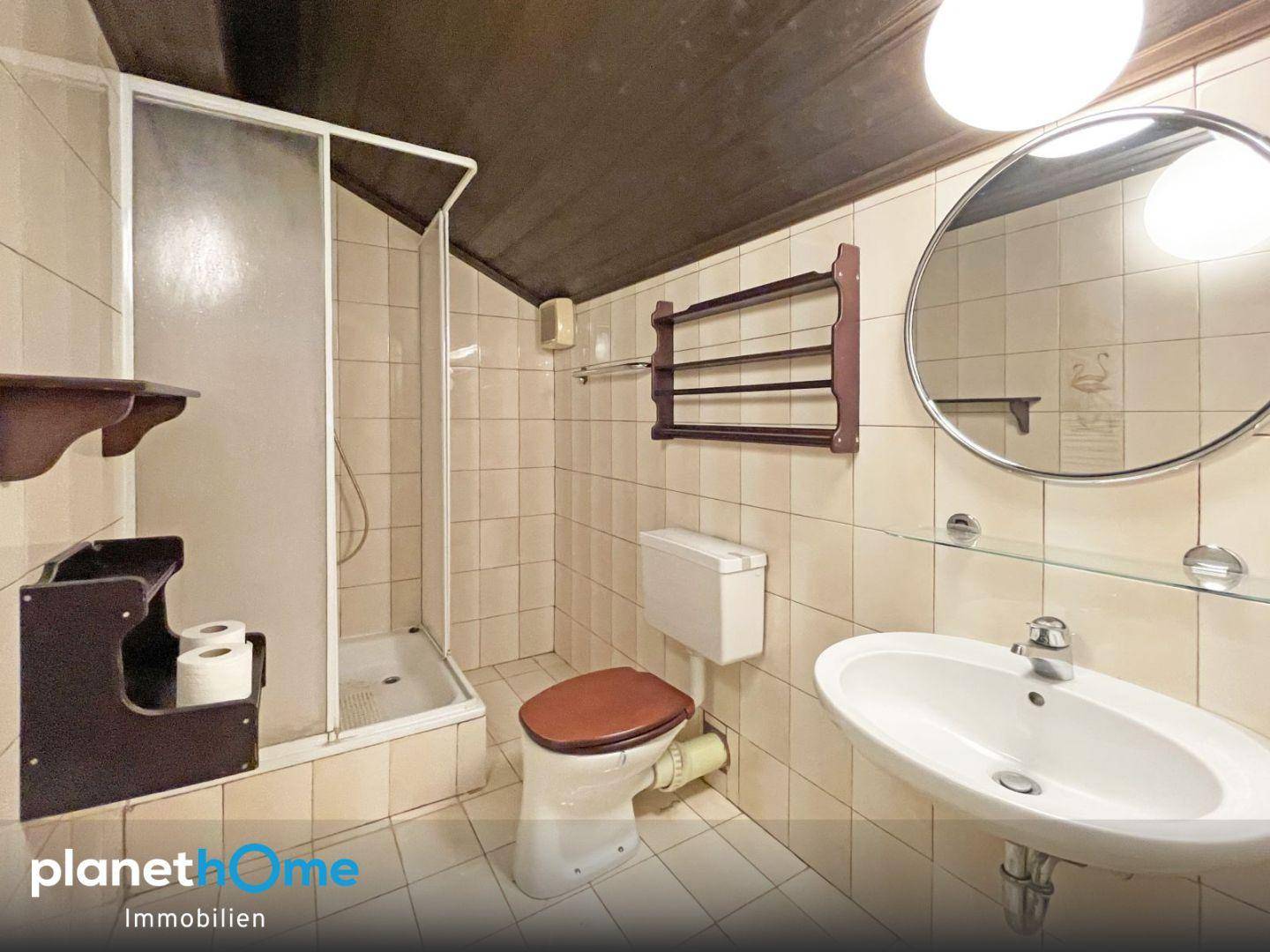 Badezimmer mit Dusche, WC und Waschbecken, gefliest im traditionellen Stil, funktional und sauber.