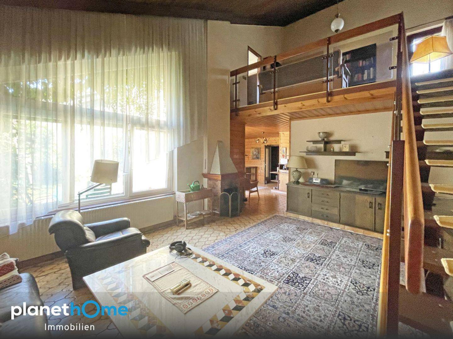 Gemütliches Wohnzimmer mit hoher Decke, Galerie und traditionellem Kamin im Landhausstil.