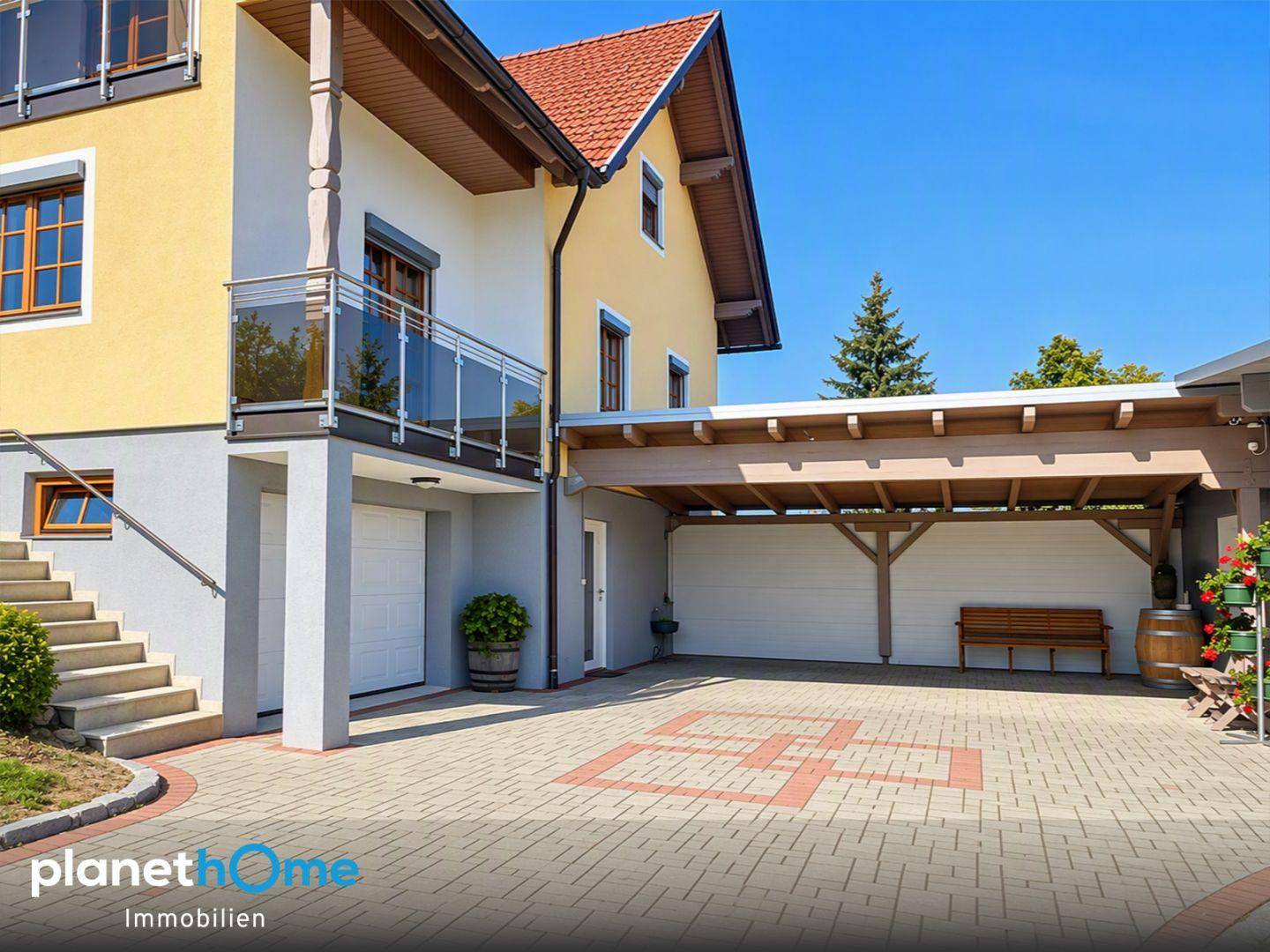 Seitenansicht des Hauses mit Balkon, Garage im Untergeschoss und überdachtem Carport.