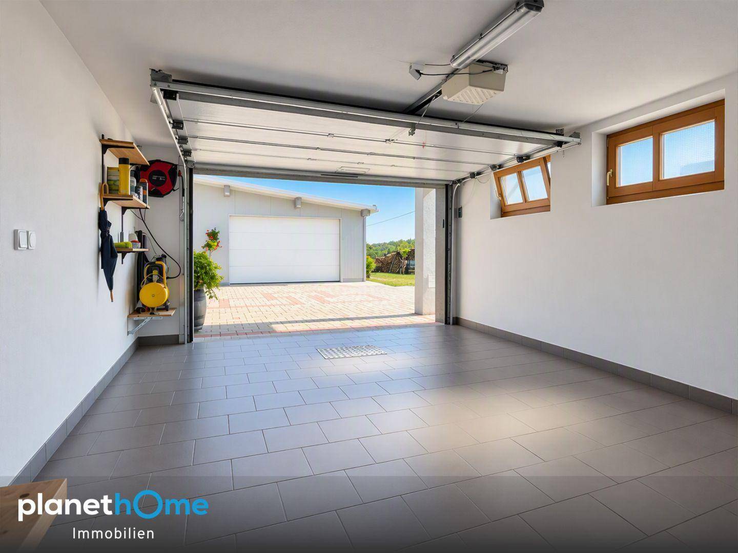 Geräumige Garage mit Fliesenboden, automatischem Tor und Fenster.