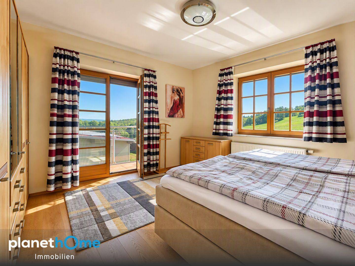 Schlafzimmer mit Holzboden, Doppelbett und Zugang zu einem Balkon mit Weitblick.