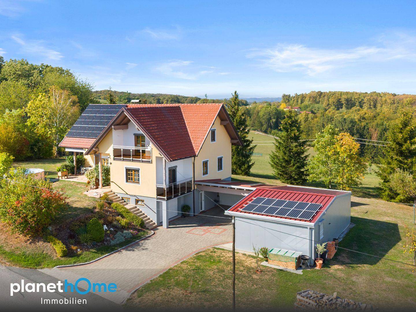 Gesamtansicht des Hauses von hinten mit Solaranlage, Carport und Garten.