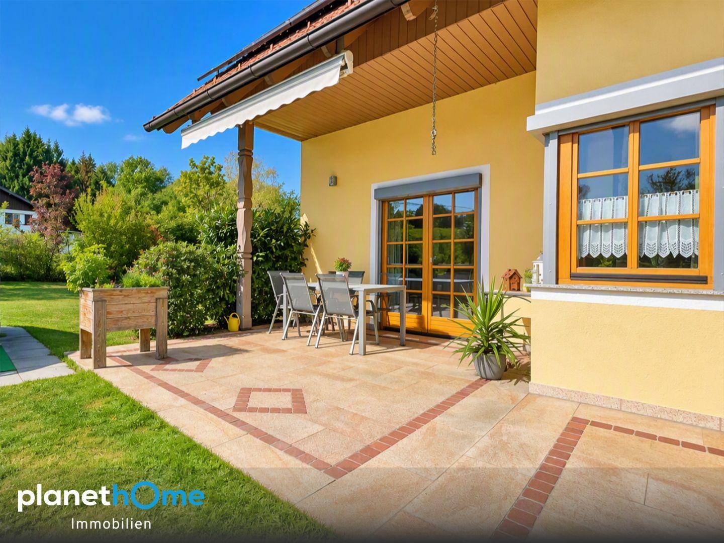 Große gepflasterte Terrasse mit Gartenmöbeln, Markise und Zugang zum Garten.
