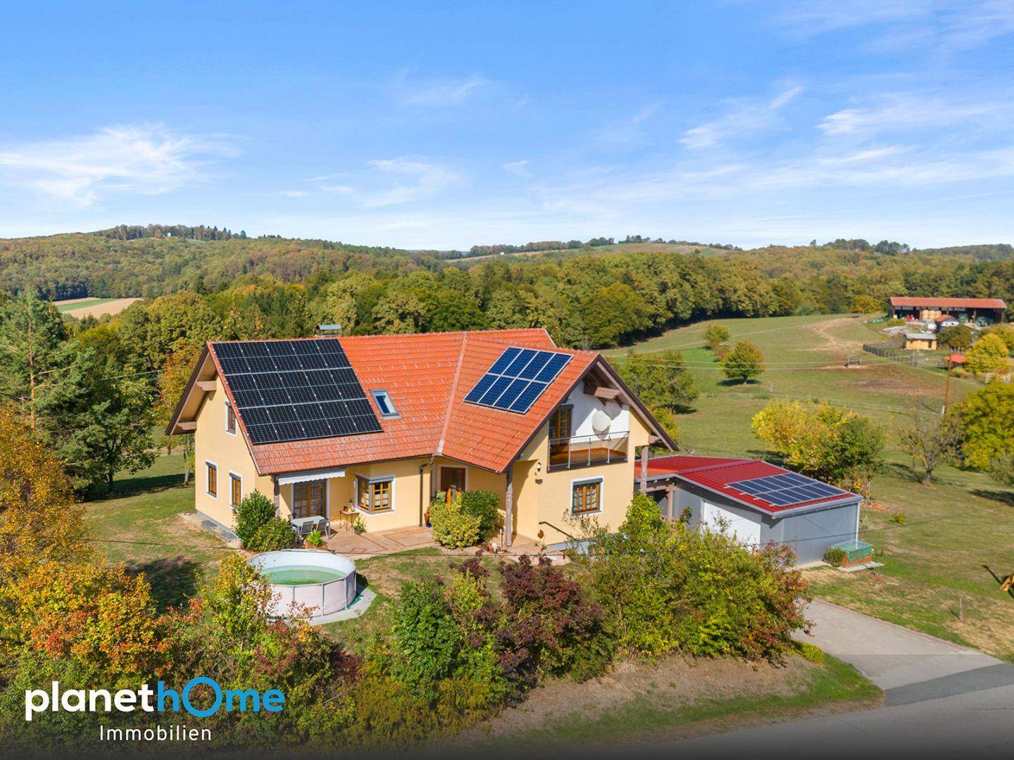 Nahaufnahme des Einfamilienhauses mit Solarmodulen auf dem Dach und einem kleinen Pool im Garten.